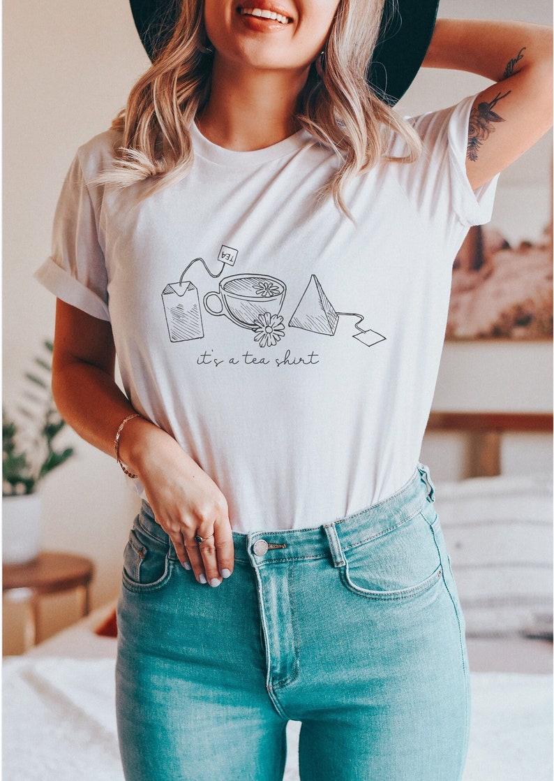 May include: White t-shirt with a black line drawing of a teacup, tea bag, and the text "it's a tea shirt".