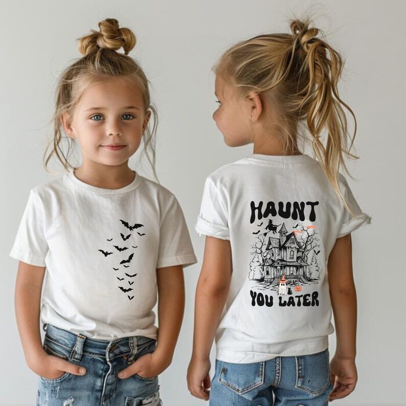 May include: White t-shirts with Halloween-themed graphics. One shirt features a descending flock of black bats. The other shirt displays a haunted house, witch, ghost, and the text "Haunt You Later."