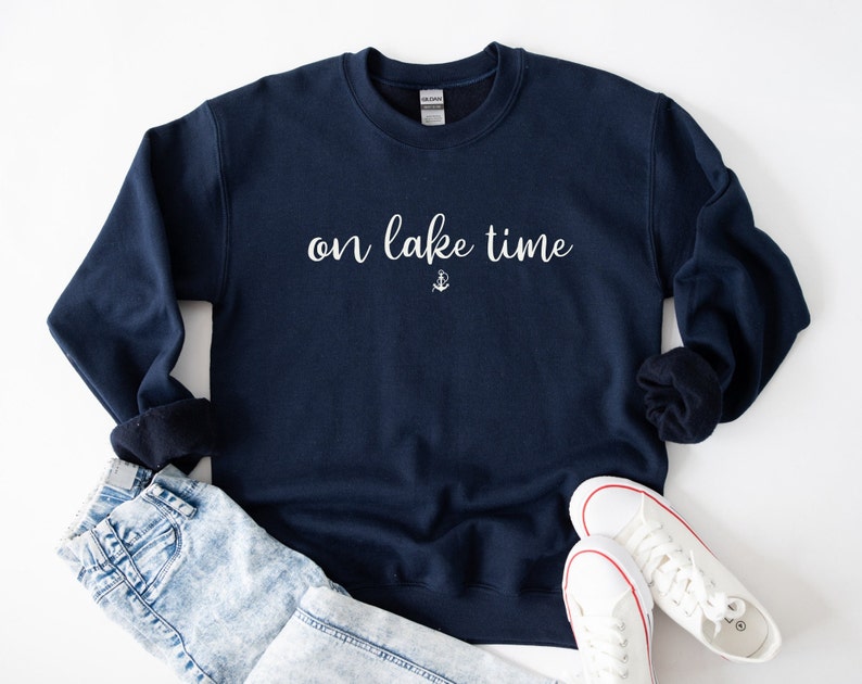 Puede incluir: Una sudadera azul marino con el texto "on lake time" en letras blancas y un peque&ntilde;o s&iacute;mbolo de ancla debajo del texto.