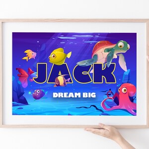 May include: A blue and purple underwater scene with a yellow, blue, and black name "JACK" in bold letters. The text "DREAM BIG" is below the name. There are various cartoon fish, an octopus, and a turtle in the scene.