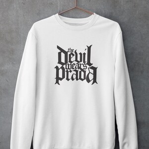 May include: White sweatshirt with black text that reads "the devil wears prada" in a gothic font.