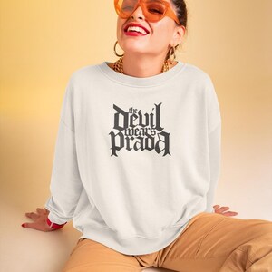 May include: White sweatshirt with a black graphic print that reads "the devil wears prada" in a gothic font.