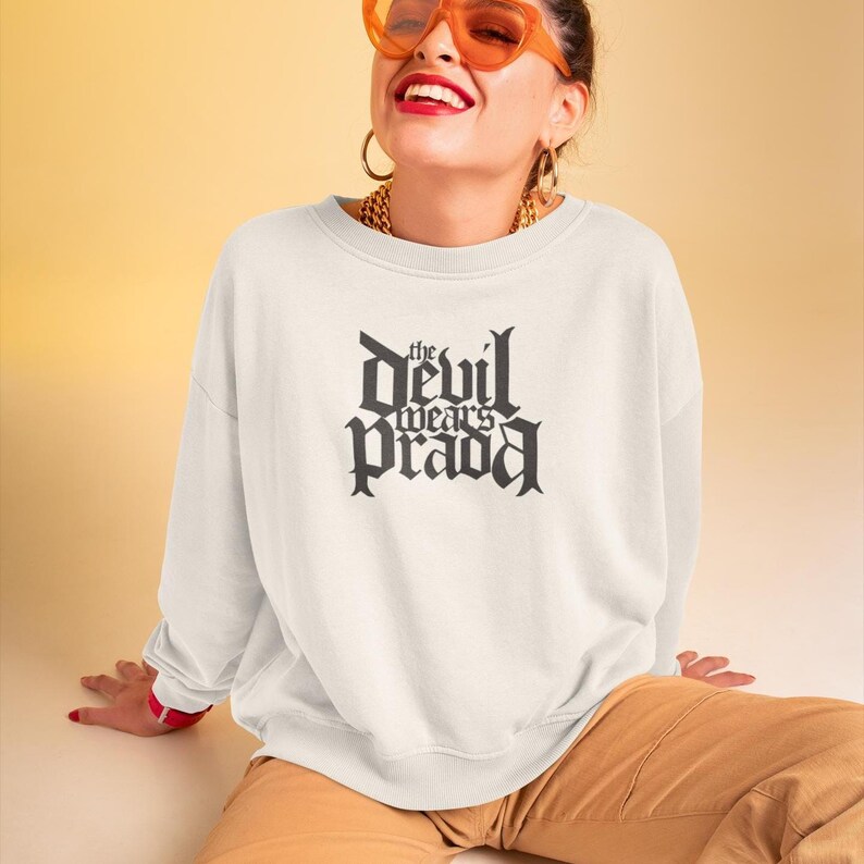 May include: White sweatshirt with a black graphic print that reads "the devil wears prada" in a gothic font.