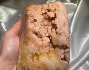 May include: A large, pink and brown geode with a large opening revealing a cluster of smaller crystals inside.