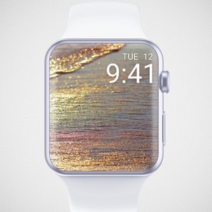 Könnte beinhalten: Eine weiße Apple Watch mit einem silbernen Gehäuse und einem digitalen Zifferblatt, das die Zeit 9:41 anzeigt. Das Hintergrundbild ist eine Strandszene mit goldenem Sand und blauem Wasser.