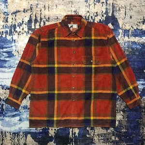 May include: A long-sleeved, button-down shirt in a plaid pattern. The shirt features a colour palette of red, brown, yellow, and navy blue. It has a chest pocket and a collar. The shirt is made of a corduroy-like material.