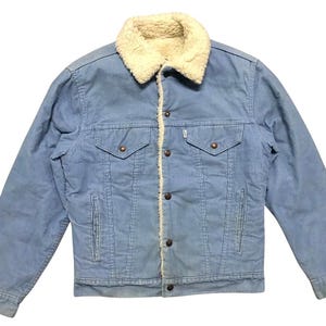 May include: Light blue corduroy jacket with a cream-colored sherpa collar and lining. The jacket has two chest pockets and two side pockets. It features a button-up front and a Levi's brand tag.