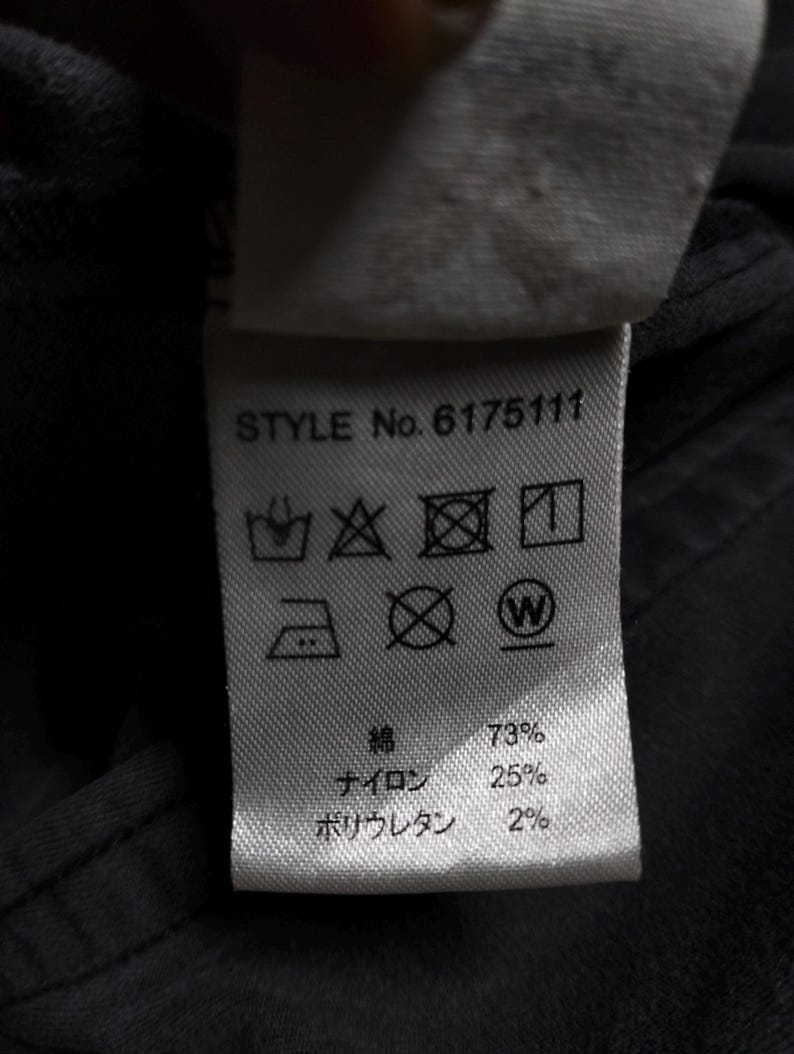 Puede incluir: Primer plano de una etiqueta de ropa con el texto "STYLE No. 6175111". La etiqueta muestra s&iacute;mbolos de cuidado y la composici&oacute;n de la tela: 73% algod&oacute;n, 25% nailon y 2% poliuretano.