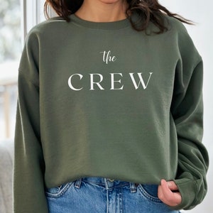 May include: A green sweatshirt with the text "the CREW" in white lettering.