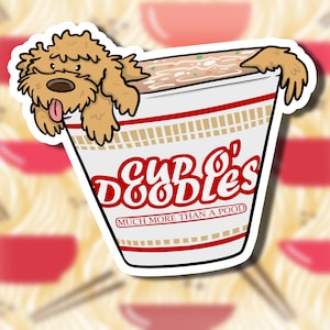 Könnte beinhalten: Ein Aufkleber mit einem braunen und weißen Doodle-Hund, dessen Kopf aus einer roten und weißen Tasse Nudeln ragt. Die Tasse trägt die Aufschrift "Cup O' Doodles" und "Much More Than A Pood".