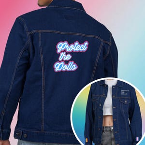 May include: Dark blue denim jacket with the text "Protect the Dolls" in a pink and blue font on the back. The jacket has a classic design with button closures, pockets, and a small rainbow flag detail on the sleeve.
