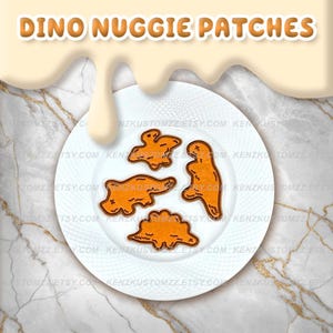 May include: A white plate with four orange dinosaur-shaped patches. The patches are outlined in brown. The text "DINO NUGGIE PATCHES" is at the top of the image in orange letters.