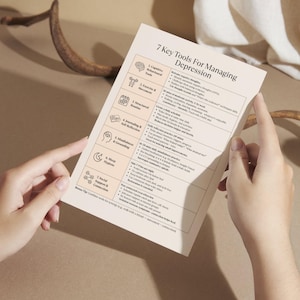 Person holding Depression Tools printable worksheet, beige CBT-based mental health cheat sheet for daily emotional support