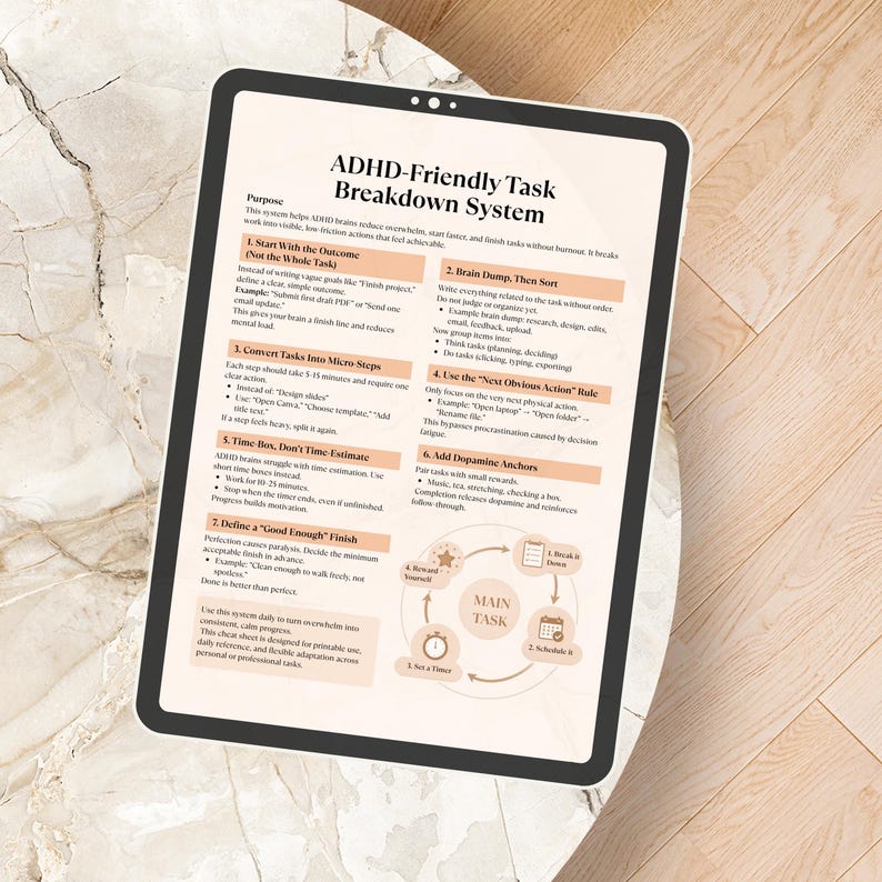 May include: A digital tablet displays a document titled "ADHD-Friendly Task Breakdown System." The document outlines steps for task management, including starting with the outcome, breaking tasks into micro-steps, and using dopamine anchors. The tablet rests on a light-colored surface.