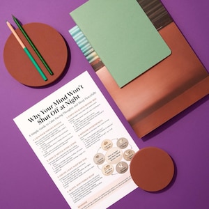 Puede incluir: Vista a&eacute;rea sobre una superficie p&uacute;rpura con una gu&iacute;a titulada "Why Your Mind Won't Shut Off at Night". Incluye un cuaderno verde, un posavasos marr&oacute;n y dos l&aacute;pices. Los l&aacute;pices son verdes y melocot&oacute;n. La gu&iacute;a ofrece consejos.