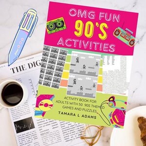 May include: A colorful activity book titled "OMG FUN 90's ACTIVITIES" with a pink cover and retro graphics. The book is open on a newspaper with a cup of coffee and a blue pen. The book is for adults with 50 90s themed games and puzzles.