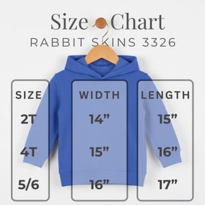 May include: A blue children's hoodie with a size chart. The chart shows measurements for sizes 2T, 4T, and 5/6. Width measurements are 14", 15", and 16", respectively. Length measurements are 15", 16", and 17". The text "Size Chart" and "RABBIT SKINS 3326" are also visible.