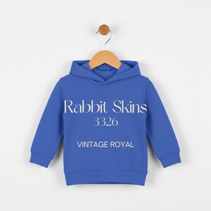 May include: A blue hooded sweatshirt with the text "Rabbit Skins 3326 VINTAGE ROYAL" in white. The sweatshirt is hanging on a wooden hanger against a white background. The garment has long sleeves and a hood.