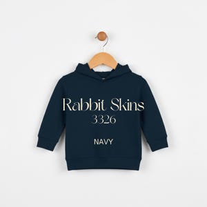May include: Navy blue hooded sweatshirt with the text "Rabbit Skins 3326 NAVY". The sweatshirt is hanging on a wooden hanger against a white background. The sweatshirt has long sleeves and a hood.