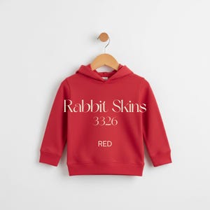 May include: A red hooded sweatshirt with the text "Rabbit Skins 3326 RED". The sweatshirt is hanging on a wooden hanger against a white background. The sweatshirt has long sleeves and a ribbed hem and cuffs.