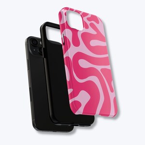 May include: A black phone with a black case and a pink and light pink swirled phone case. The phone case has a glossy finish and a unique, abstract design. The phone and cases are displayed against a white background.