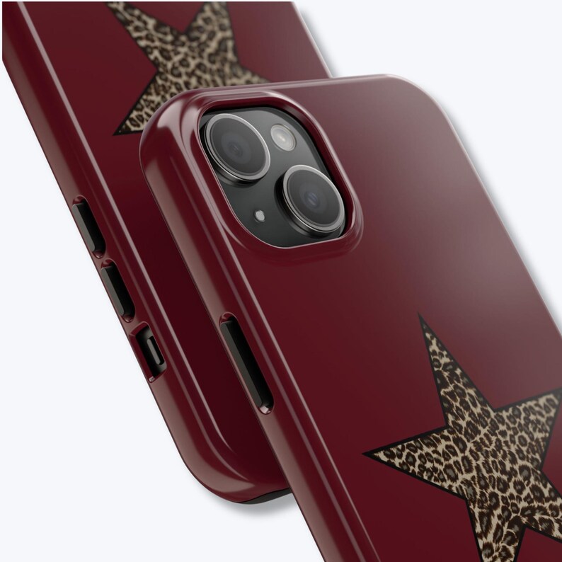 Pu&ograve; includere: Custodie per telefono bordeaux con finitura lucida. Ogni custodia presenta un grande design a stella con un motivo leopardato. Le custodie hanno un design elegante e moderno e sono mostrate ad angolo, evidenziando la fotocamera e i pulsanti laterali.