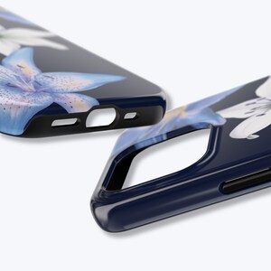 May include: Two navy blue phone cases with a floral design. The cases feature a close-up of a blue and white flower with yellow accents. The cases have a glossy finish and black edges.