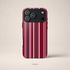 Op de afbeelding: Een smartphonehoesje met een verticaal gestreept patroon in tinten donkerrood, bordeaux en crème. Het hoesje heeft een zwarte rechthoekige cameramodule aan de bovenkant met drie ronde lensopeningen en een flitser. De tekst Cabernet staat eronder.