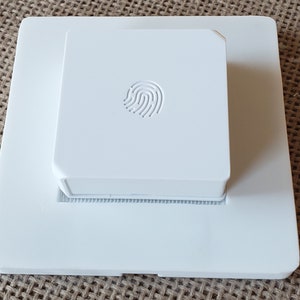 May include: White wall plate with a white square fingerprint sensor mounted on top.