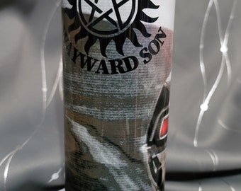 May include: A white tumbler with a black and white graphic of a pentagram with a sunburst around it. The text "Carry On My Wayward Son" is printed around the graphic. The tumbler is sitting on a white pedestal.