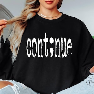 May include: Black sweatshirt with white text that reads "continue" in a distressed font.