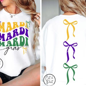 Könnte beinhalten: Weißes Sweatshirt mit dem Text "MARDI MARDI MARDI gras" in Gelb, Lila und Grün. Auf der Rückseite befinden sich drei Schleifendesigns in Gelb, Lila und Grün. Ein festliches Design für Mardi Gras-Feiern.