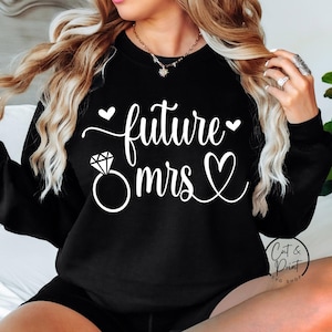 Może przedstawiać: Czarna bluza z białym napisem "future mrs", pierścionkiem z diamentem i sercami. Obraz zawiera również logo "Cat & Print SVG Shop".