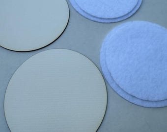 May include: Two light beige wooden circles and two stacks of light blue felt circles are arranged on a gray surface. The wooden circles have a dark brown edge. The felt circles are stacked in pairs.