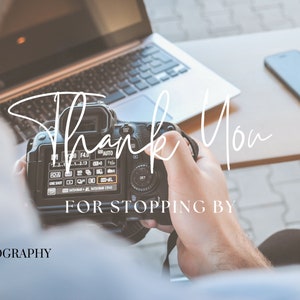May include: A person holding a black DSLR camera with the text "Thank You for Stopping By" on the screen. The camera is in focus, and the person's hand is blurred. The background is out of focus and shows a laptop and a cell phone.