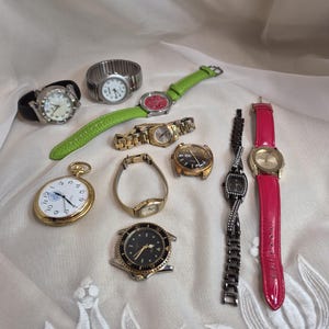 Puede incluir: Una colección de diez relojes de pulsera y un reloj de bolsillo con diversos diseños, incluyendo una correa de cuero verde brillante, una correa de cuero rosa intenso, bandas de metal dorado, eslabones negros y cajas plateadas.