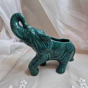 May include: A white ceramic mug with a black handle and the text "But First, Coffee" in a black, bold font. The mug is on a wooden surface.