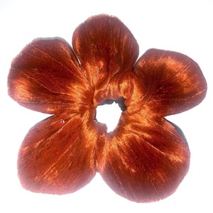 May include: A large, rust-colored velvet scrunchie shaped like a flower with five petals.