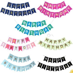 May include: A collection of colorful "Happy Birthday" banner flags in various colors, including blue, pink, green, and black. Each banner has gold lettering and is strung on a white string, perfect for birthday party decorations.