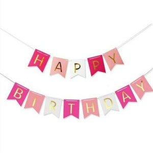 May include: A festive banner with the words "HAPPY BIRTHDAY" in gold lettering. The banner features pink, white, and light pink pennant flags strung on a white string, perfect for birthday celebrations.