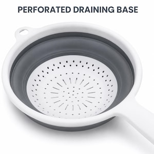 May include: A collapsible colander featuring a white rim and handle with a dark grey flexible body. The interior base is white with a perforated draining base design. The text PERFORATED DRAINING BASE is visible at the top of the image.