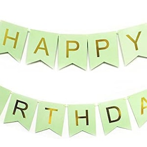 May include: A light green banner with gold lettering that reads "HAPPY BIRTHDAY". The banner is made of individual pennants strung together with a white string, perfect for birthday celebrations.