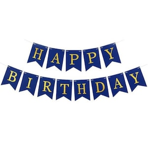 May include: A blue and gold Happy Birthday banner. The banner is made of individual pennant flags strung together with white string. Each flag is a deep blue color with gold glitter lettering.