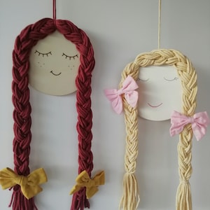 Peut inclure: Deux poupées en bois avec des cheveux en laine, l'une avec de la laine rouge et un nœud jaune, l'autre avec de la laine blonde et un nœud rose.