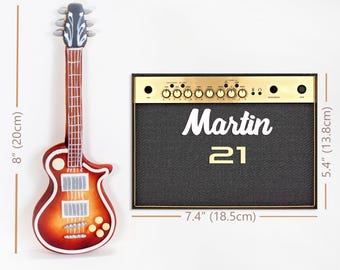 May include: A sunburst electric guitar measuring 8 inches tall and a rectangular amplifier with a gold control panel, black speaker grille, and the white text "Martin 21" measuring 7.4 inches wide by 5.4 inches tall.