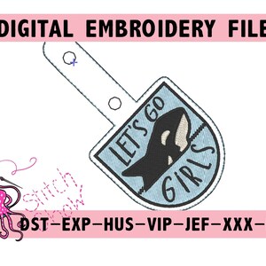 Può includere: Un ricamo blu e bianco con un'orca nera e il testo "Let's Go Girls".