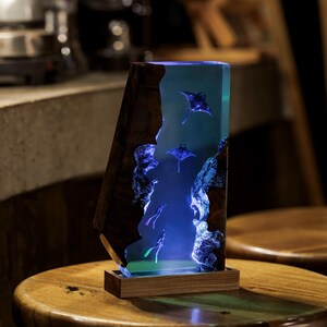 May include: A wooden lamp base with a clear resin insert featuring blue stingrays. The resin is illuminated with blue LED lights.