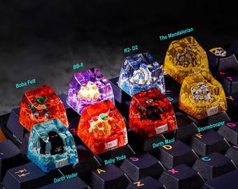 May include: A set of ten Star Wars themed keycaps, each featuring a different character from the franchise. The keycaps are made of clear resin and feature intricate details. The characters include Boba Fett, BB-8, R2-D2, The Mandalorian, Baby Yoda, Darth Vader, Darth Maul, and Stormtrooper.