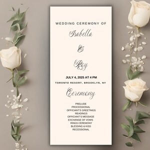 May include: A wedding ceremony program with the names Isabella and Rey, and the date July 4, 2025. The program is cream-colored with black text and is decorated with white roses and greenery. The program includes the ceremony details.