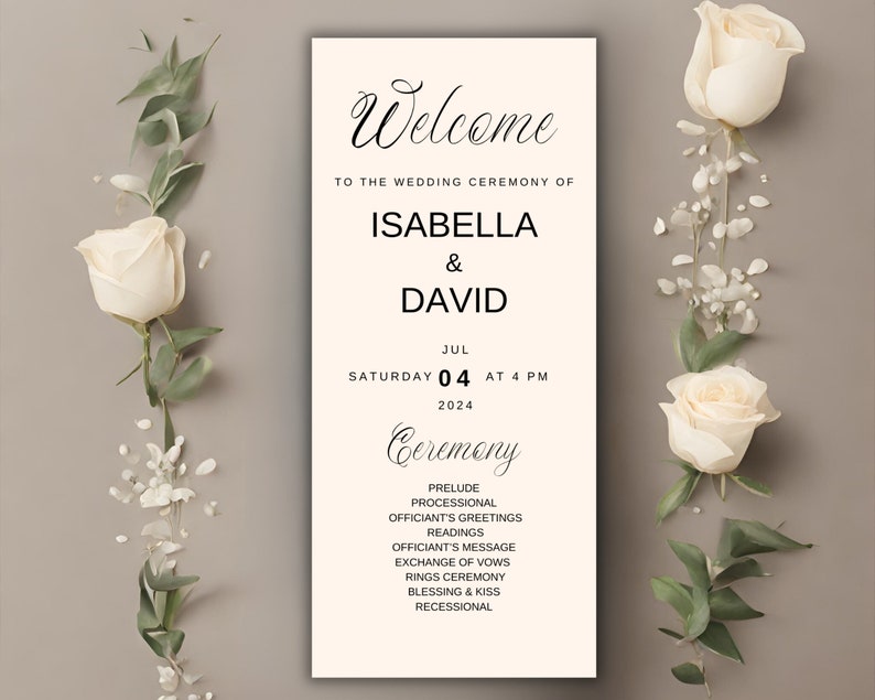 May include: A wedding ceremony sign with the names Isabella & David, date, and time. The sign is cream-colored with black text and floral accents. White roses and greenery frame the sign.